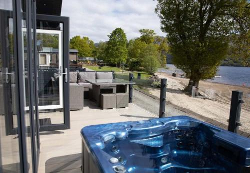 a hot tub on a patio with a view of the water at Loch Lomond Holiday Park in Inversnaid
