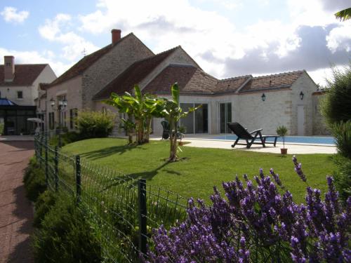 a house with a fence in front of a yard with purple flowers at La Motte Melleraye in Donnery