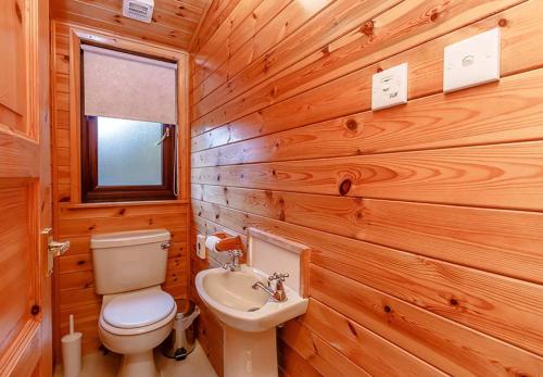 a wooden bathroom with a toilet and a sink at Loch Lomond Holiday Park in Inversnaid