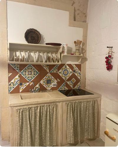 a kitchen with a counter with tiles on the wall at La Ramasola in Fasano