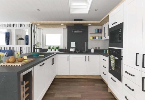 a kitchen with white cabinets and black appliances at Loch Lomond Holiday Park in Inversnaid