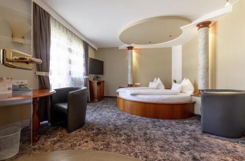 ヴァルスにあるホテル ヒンメルライヒのベッドとデスクが備わるホテルルームです。