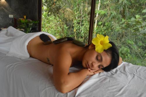 a woman laying on a bed with a yellow flower on her head at Suchipakari Amazon Eco -Lodge & Jungle Reserve in Puerto Misahuallí