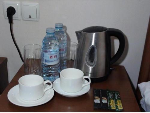 a table with two cups and a coffee pot and water at EUPHORIA Mariam in Tbilisi City