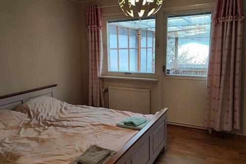 Schlafzimmer mit einem Bett, einem Fenster und einem Kronleuchter in der Unterkunft Sollenatuna cozy & spacial house in Sollentuna