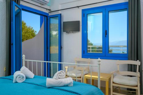 een slaapkamer met een bed, een stoel en ramen bij Havania Apartments in Agios Nikolaos