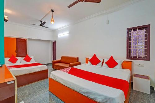 ein Hotelzimmer mit 2 Betten und einem Stuhl in der Unterkunft OYO 82990 DHANAS BEST AMBIENCE in Puducherry