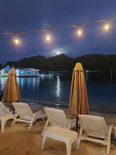eine Gruppe von Stühlen und Sonnenschirmen am Strand in der Nacht in der Unterkunft Casa de playa in Isla Grande