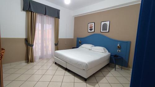 Dormitorio azul y blanco con cama y ventana en Hotel Al Faro, en Licata