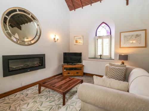 a living room with a couch and a tv and a mirror at Frogwell Chapel in Callington