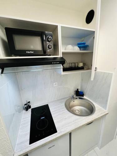 uma pequena cozinha com um lavatório e um micro-ondas em T1 - Le Papangue 5* - neuf, vue jardin, 8’ airport em Sainte-Clotilde