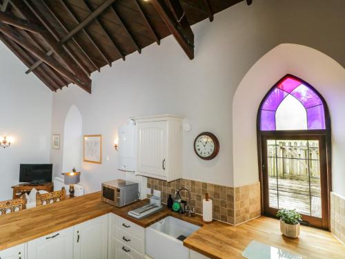 a kitchen with a clock on the wall and a window at Frogwell Chapel in Callington