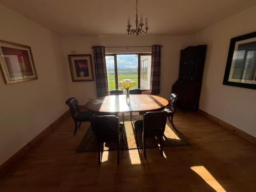 a dining room with a table and chairs and a window at The Bungalow Knockreagh Farm Kilkenny R95AX50 in Callan