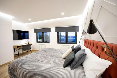 1 dormitorio con 1 cama, escritorio y ventanas en Lucus Skyline, en Lugo