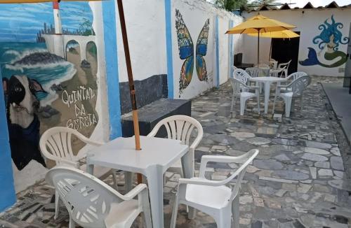 un patio con mesas y sillas blancas y una sombrilla en hostel quintal da sereia, en Salvador
