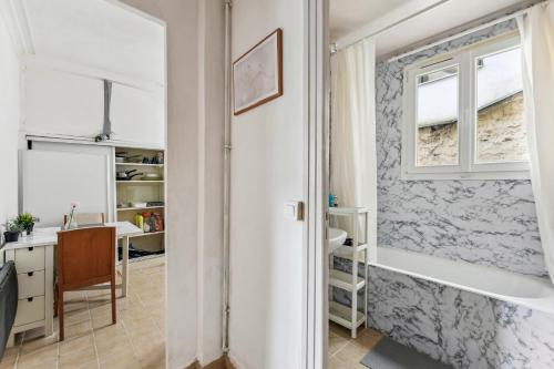 La salle de bains est pourvue d'une baignoire à côté d'une fenêtre. dans l'établissement Superbe appartement à Paris, à Paris