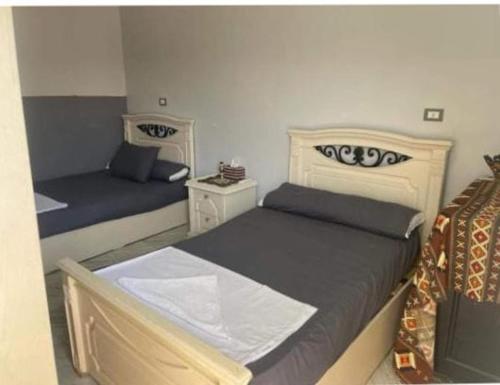 1 dormitorio con 2 camas y 2 mesitas de noche en Bakar House, en Asuán