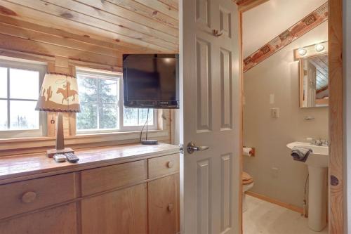 een badkamer met een televisie op een aanrecht met een wastafel bij Wanderlust Cabin in Lead