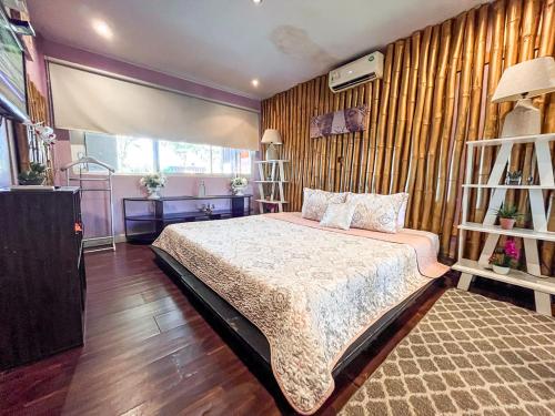 1 dormitorio con 1 cama y pared de madera en Bambú Lodge San Jose Airport en Ciudad Cariari
