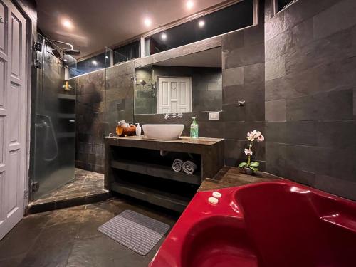 uma casa de banho com uma banheira vermelha e um lavatório. em Bambú Lodge San Jose Airport em Ciudad Cariari