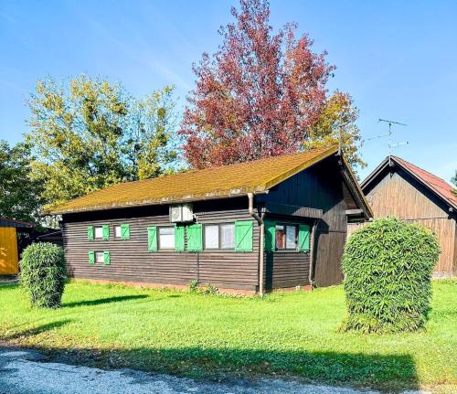 a small wooden house with green windows on a yard at Schmelcer house in Terme Čatež in Čatež ob Savi