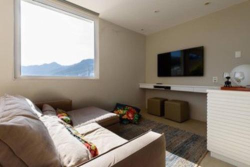 uma sala de estar com um sofá e uma grande janela em Cobertura Frente Lagoa vista excepcional Rio de Janeiro no Rio de Janeiro