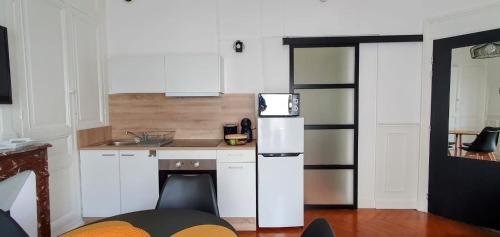 a kitchen with white cabinets and a white refrigerator at Entre 2 flots 1 in Le Tréport