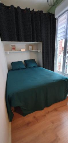 sypialnia z łóżkiem z niebieskimi poduszkami i oknem w obiekcie Entre 2 flots 1 w mieście Le Tréport