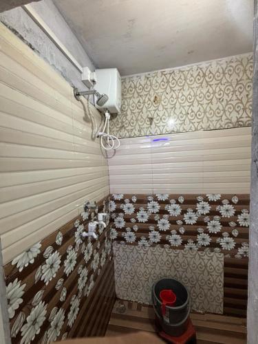 a room with a shower with flowers on the wall at sun guest house 2 in Ujjain