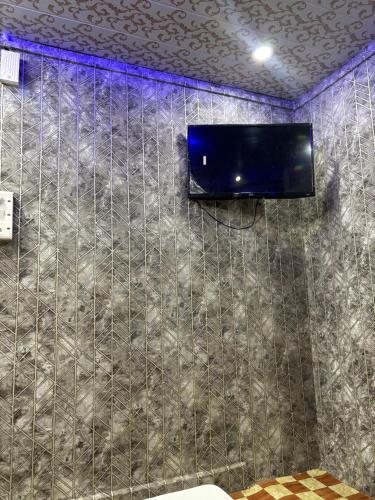 a bathroom with a tv on a tiled wall at sun guest house 2 in Ujjain