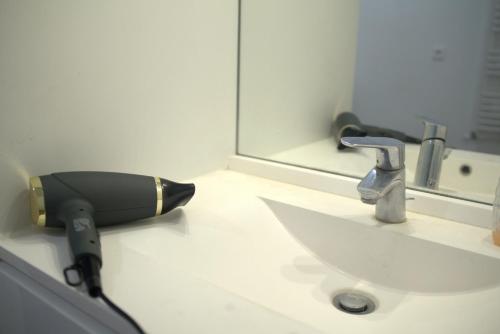 a hair dryer is sitting on a bathroom sink at Chic Retreat near Paris in Saint-Ouen