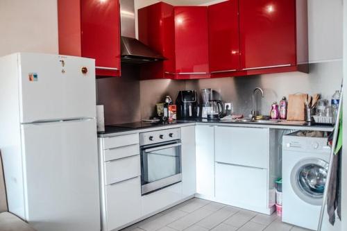 a kitchen with white appliances and red cabinets at Chic Retreat near Paris in Saint-Ouen