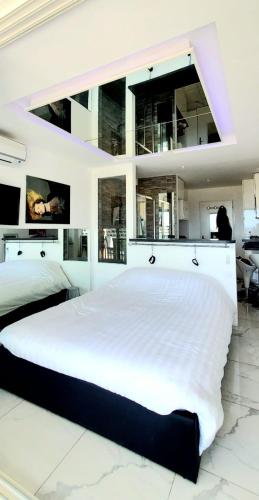 - une grande chambre blanche avec un grand lit blanc dans l'établissement Naturiste Cap d'Agde Héliopolis F 72, au Cap d'Agde