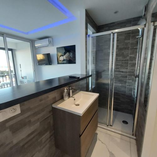 une salle de bain avec un lavabo et une douche dans l'établissement Naturiste Cap d'Agde Héliopolis F 72, au Cap d'Agde