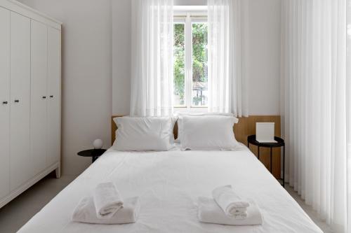 Un dormitorio blanco con una cama blanca grande con toallas. en Rothschild 69 en Tel Aviv