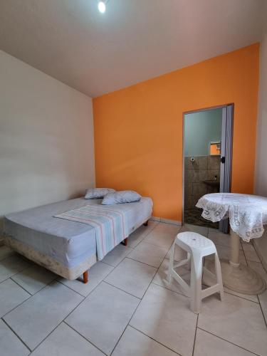 a bedroom with a bed and a table and a stool at Recanto Aconchego Itapoá in Itapoa