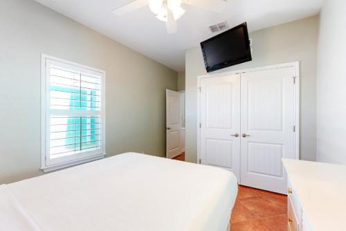 a bedroom with a white bed and a flat screen tv at Marquesas 401 in Padre Island