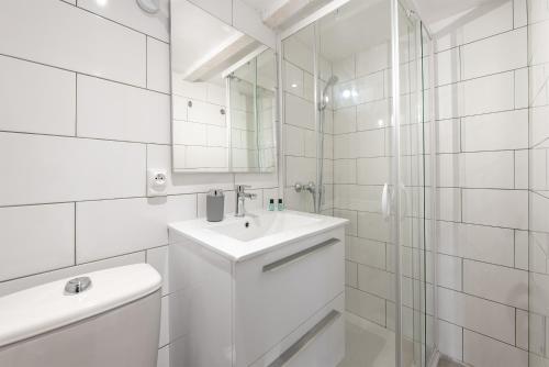 a white bathroom with a sink and a mirror at Les appartements de l'horloge in Carcassonne
