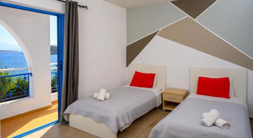 two beds in a room with a view of the ocean at Havania Apartments in Agios Nikolaos
