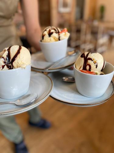 three bowls of ice cream on plates on a table at Bed and Brunsj, Sand in Sand