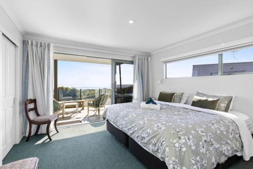een slaapkamer met een bed en een groot raam bij Oceanview on Broadway in Waihi Beach
