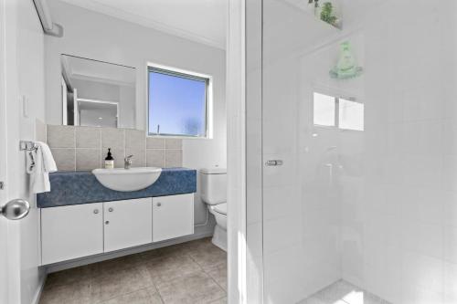 een witte badkamer met een wastafel en een toilet bij Oceanview on Broadway in Waihi Beach
