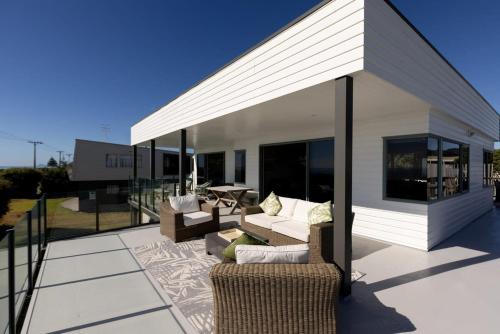 a patio with couches and chairs on a roof at Oceanview on Broadway in Waihi Beach