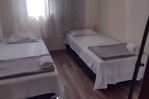 two twin beds in a small room with wooden floors at Apartamento prático, simples CDHU. in Itatiba