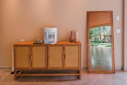 a wooden cabinet with a coffee maker on it next to a mirror at Pousada Pazuu in Ubatuba