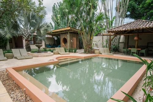 a swimming pool in a yard with chairs and trees at Pousada Pazuu in Ubatuba