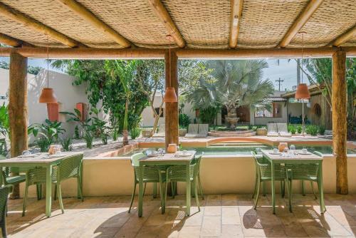 a patio with tables and chairs and a swimming pool at Pousada Pazuu in Ubatuba