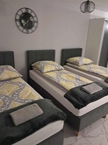 two beds in a room with a clock on the wall at Apartament Julia 1-3 os I piętro z balkonem i garażem in Kielce