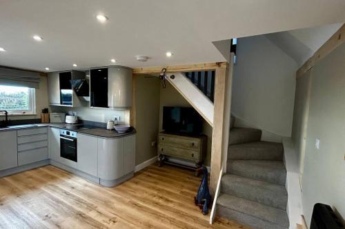 a kitchen with a staircase leading up to a stair case at The Old Workshop - a cosy country retreat in Gloucester