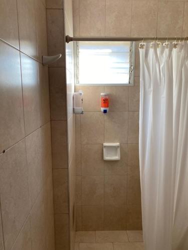 La salle de bains est pourvue d'une douche avec rideau de douche. dans l'établissement Excelencia y ubicación, à Resistencia